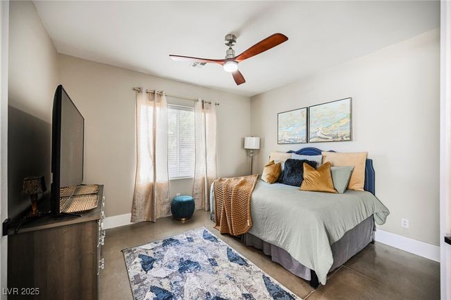 Bedroom featuring finished concrete flooring, ceiling fan, baseboards, and visible vents | Image 25