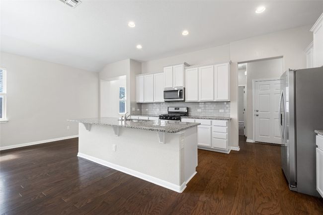 Kitchen featuring stainless steel appliances, dark wood-style flooring, tasteful backsplash, a kitchen breakfast bar, and recessed lighting | Image 16