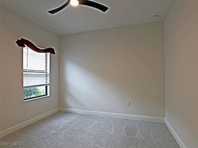 Carpeted empty room featuring a ceiling fan, a smoke detector, and baseboards | Image 18