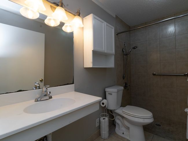 Full bath featuring tiled shower, vanity, tile patterned flooring, and a textured ceiling | Image 15