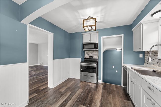 Kitchen with a wainscoted wall, appliances with stainless steel finishes, dark wood-type flooring, and a sink | Image 12