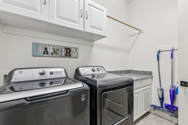 Washroom featuring cabinet space, washer and clothes dryer, and light tile patterned flooring | Image 26