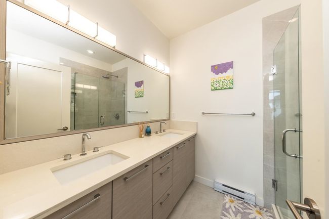 Full bath with a baseboard radiator, double vanity, a stall shower, baseboards, and tile patterned flooring | Image 15