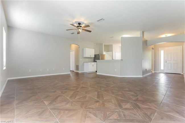 Unfurnished living room with arched walkways and a ceiling fan | Image 5