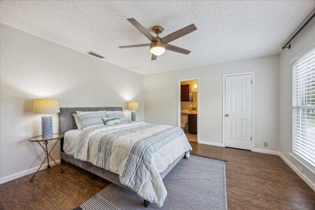 Bedroom featuring wood finished floors, a textured ceiling, ceiling fan, and ensuite bath | Image 17