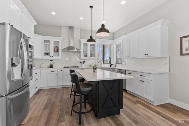 Kitchen with stainless steel appliances, wall chimney exhaust hood, backsplash, white cabinetry, and recessed lighting | Image 19