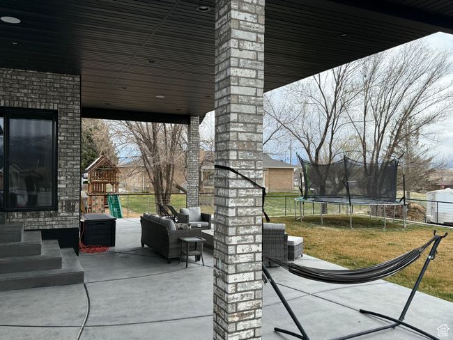 View of patio with a trampoline, a playground, an outdoor hangout area, and fence | Image 23