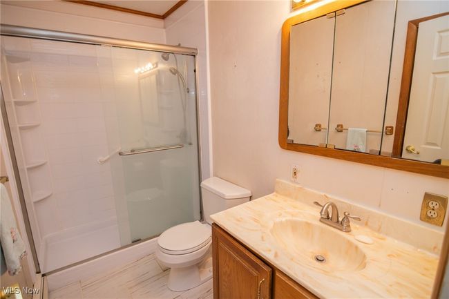 Full bath featuring a stall shower, vanity, toilet, and ornamental molding | Image 20