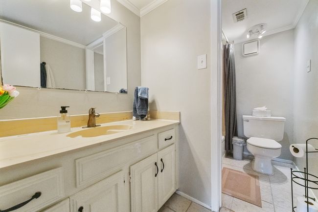 Full bathroom with crown molding, toilet, vanity, baseboards, and tile patterned flooring | Image 13