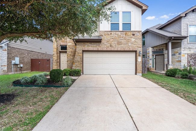 View of front of property featuring stone siding, driveway, board and batten siding, and an attached garage | Image 40