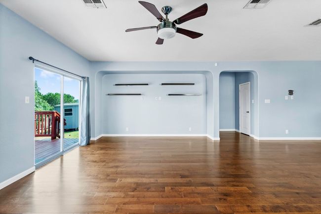 Unfurnished living room featuring a ceiling fan, arched walkways, and dark wood-style floors | Image 13
