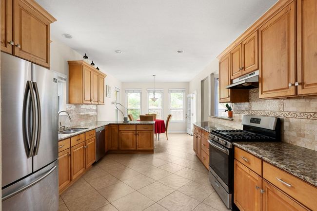 Kitchen with a sink, a peninsula, under cabinet range hood, dark stone counters, and stainless steel appliances | Image 10