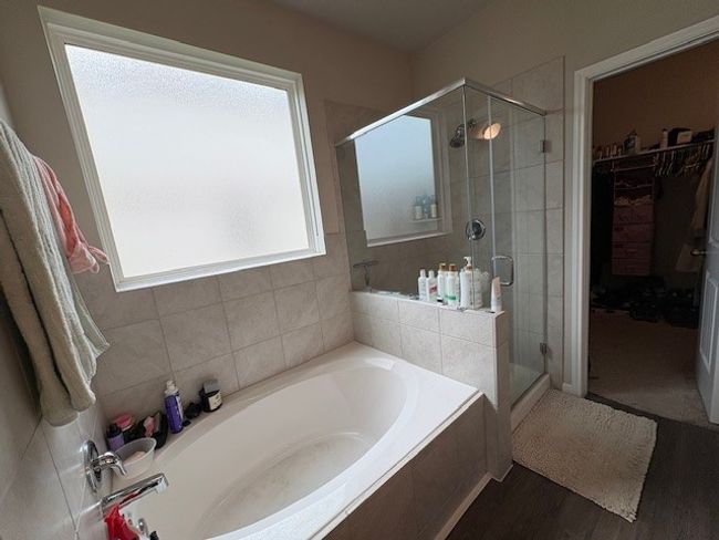 Bathroom with a bath, a shower stall, a walk in closet, and wood finished floors | Image 8