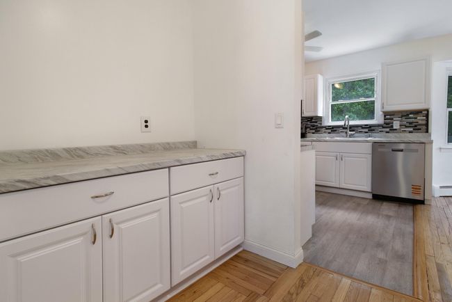 Kitchen featuring dishwasher, backsplash, light wood-type flooring, and white cabinetry | Image 15