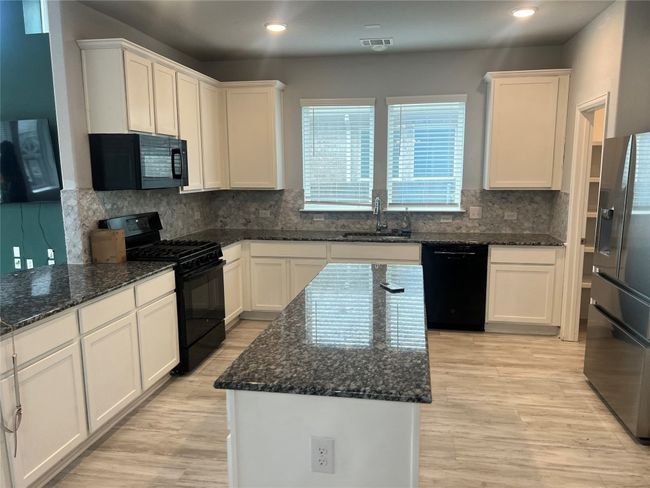 Kitchen featuring black appliances, white cabinetry, backsplash, light wood-style flooring, and recessed lighting | Image 16