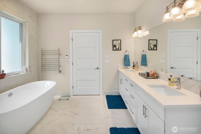 Double sinks, towel warmer, and door to the primary bedroom beyond. | Image 18