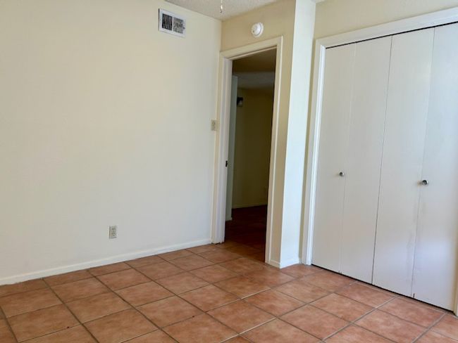 Unfurnished bedroom with light tile patterned floors, a closet, and visible vents | Image 11