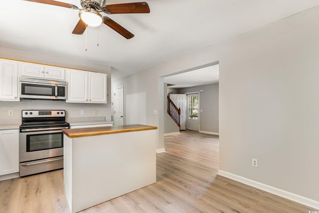 Kitchen featuring white cabinets, a ceiling fan, light wood-style floors, and appliances with stainless steel finishes | Image 6