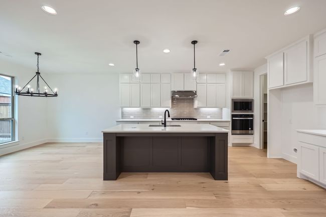 Kitchen featuring under cabinet range hood, a sink, light countertops, tasteful backsplash, and appliances with stainless steel finishes | Image 11