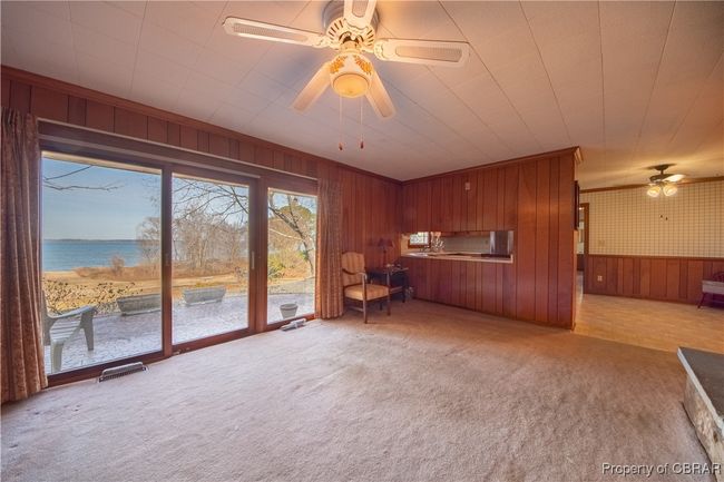 Unfurnished living room featuring ornamental molding, a water view, light colored carpet, and ceiling fan | Image 9