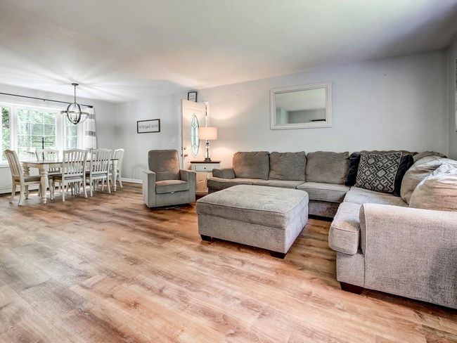 Living area with wood finished floors and a chandelier | Image 7