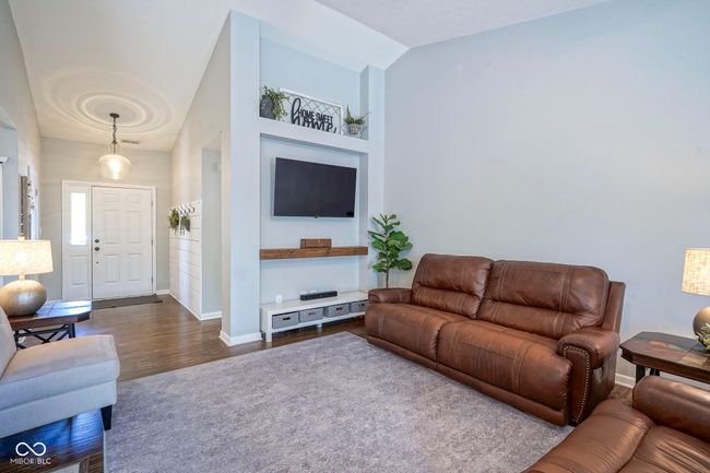living room with high vaulted ceiling, dark wood finished floors, and baseboards | Image 8