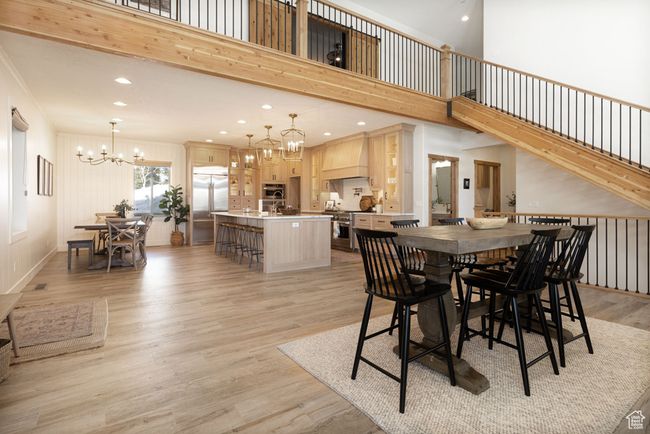 Dining area with stairs, recessed lighting, a towering ceiling, light wood-style flooring, and a notable chandelier | Image 9
