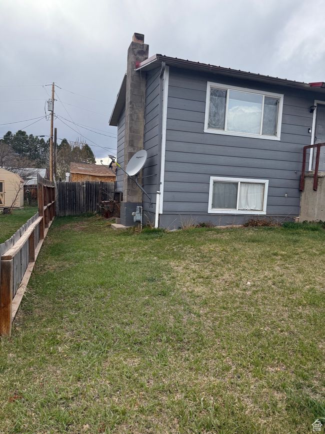 View of side of home with fence, a lawn, and a chimney | Image 6