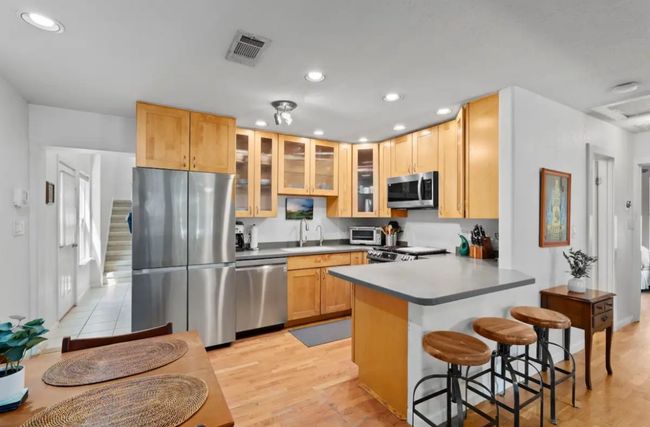 Kitchen with appliances with stainless steel finishes, a kitchen bar, recessed lighting, a peninsula, and glass insert cabinets | Image 10