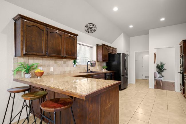 Kitchen featuring decorative backsplash, a kitchen bar, dark brown cabinetry, recessed lighting, and a peninsula | Image 14