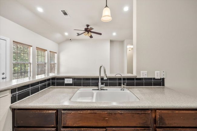 Kitchen with dark brown cabinetry, a ceiling fan, visible vents, lofted ceiling, and a sink | Image 14