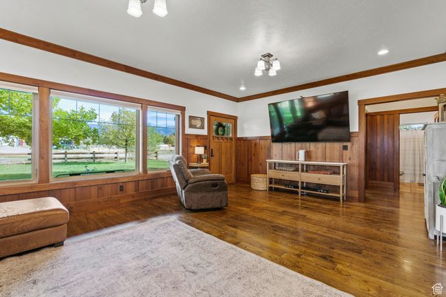 Living room with a notable chandelier, ornamental molding, dark hardwood / wood-style floors, and wood walls | Image 9