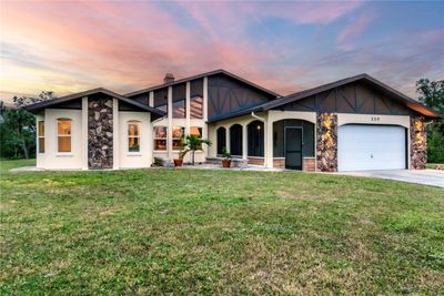 Front elevation showing the large windows, stone siding, and wood accents that really make this home stand out. | Image 1