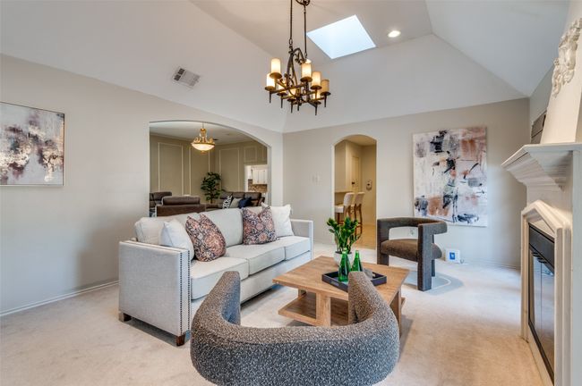 Living room featuring light carpet, visible vents, arched walkways, lofted ceiling, and a chandelier | Image 4