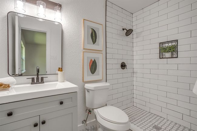 Full bathroom featuring tiled shower, vanity, and a textured wall | Image 23