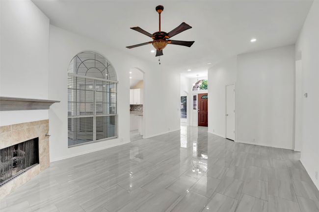 Unfurnished living room featuring ceiling fan, light tile floors, and a fireplace | Image 13