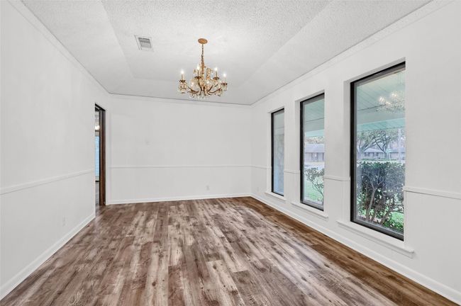 Empty room featuring wood finished floors, a chandelier, a textured ceiling, and baseboards | Image 14