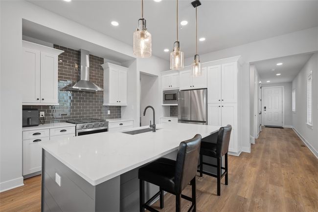 Kitchen offers eat-at island, stainless steel appliances, upgraded lighting, recessed lighting, LVP flooring. Open concept to dining area and great room | Image 6