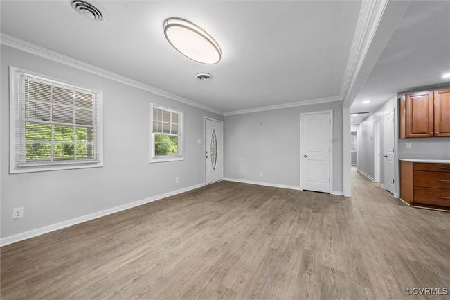 Unfurnished living room featuring visible vents, crown molding, and light wood finished floors | Image 7