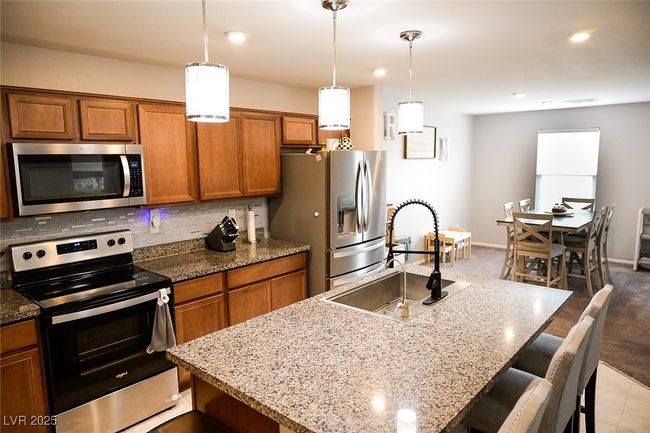 Kitchen featuring a kitchen breakfast bar, a sink, brown cabinets, and appliances with stainless steel finishes | Image 8