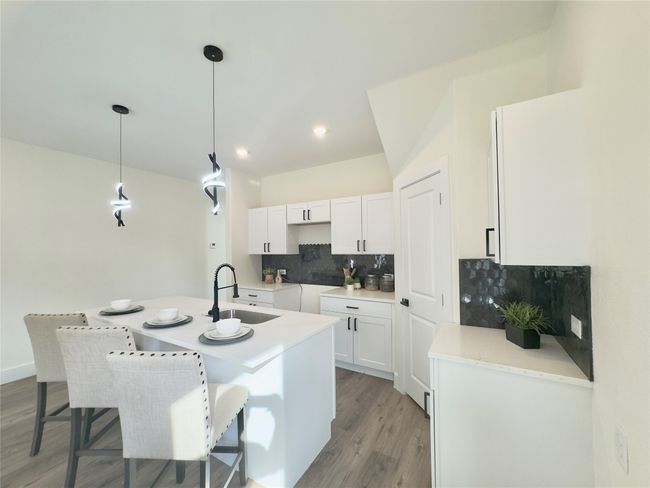 Kitchen with a sink, tasteful backsplash, light wood-type flooring, white cabinetry, and an island with sink | Image 7
