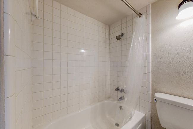 A minimalist wet room showcasing a shower, toilet, and tub, with neutral-colored tiles designed for comfort and functionality. | Image 22