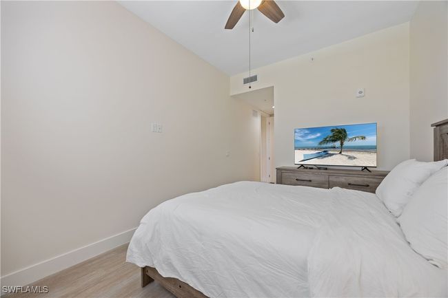 Bedroom with light wood-type flooring, baseboards, a ceiling fan, and visible vents | Image 4