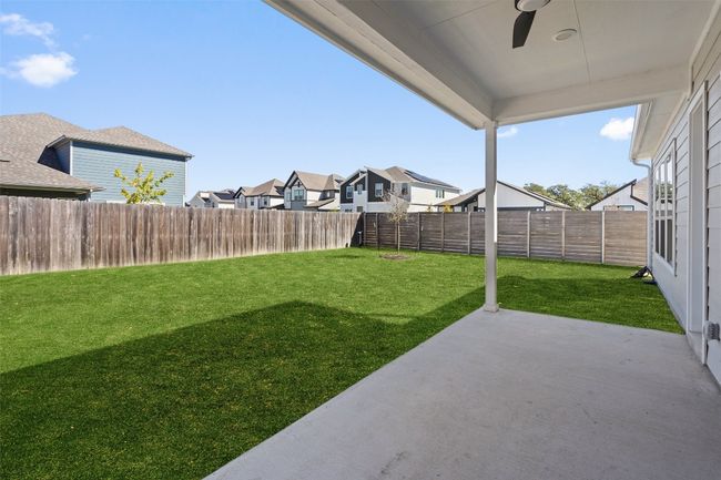 Fenced backyard with ceiling fan, a patio area, and a residential view | Image 38