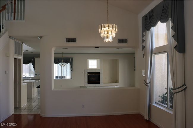 Unfurnished living room with high vaulted ceiling, a chandelier, wood finished floors, a fireplace, and arched walkways | Image 22