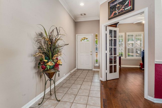 Entrance foyer featuring crown molding, baseboards, tile and hardwood flooring. | Image 6