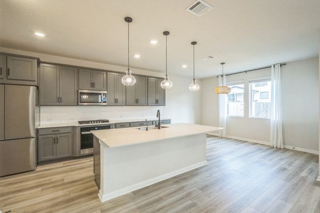 Kitchen featuring appliances with stainless steel finishes, a sink, gray cabinetry, light wood finished floors, and decorative backsplash | Image 7