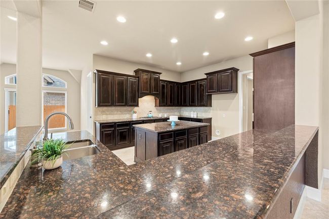 Abundant granite counter space, plenty of cabinets and still open to the family room. | Image 16