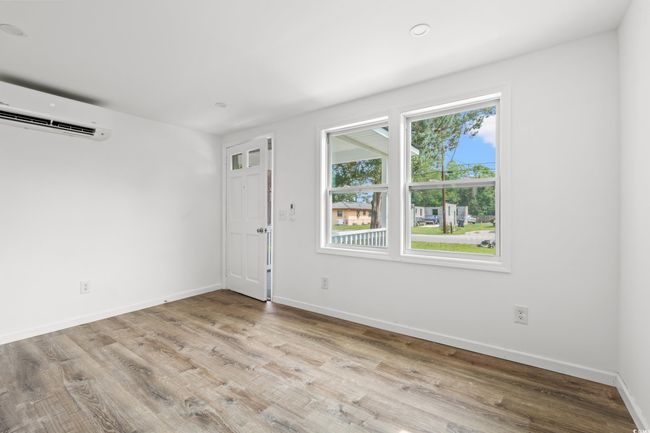 Bedroom 1 with an AC wall unit, wood finished floors, and baseboards | Image 10