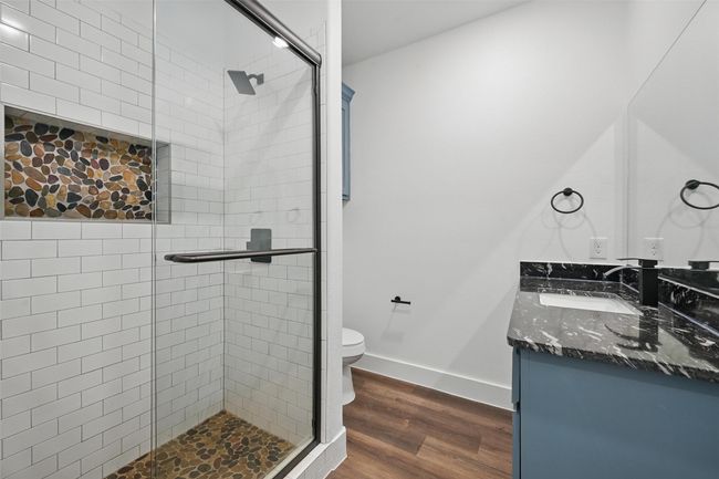 Bathroom featuring vanity, baseboards, toilet, a shower stall, and wood finished floors | Image 18